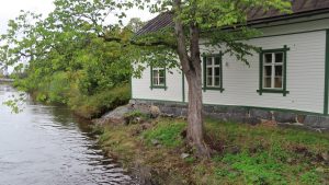 a small white house sitting next to a river