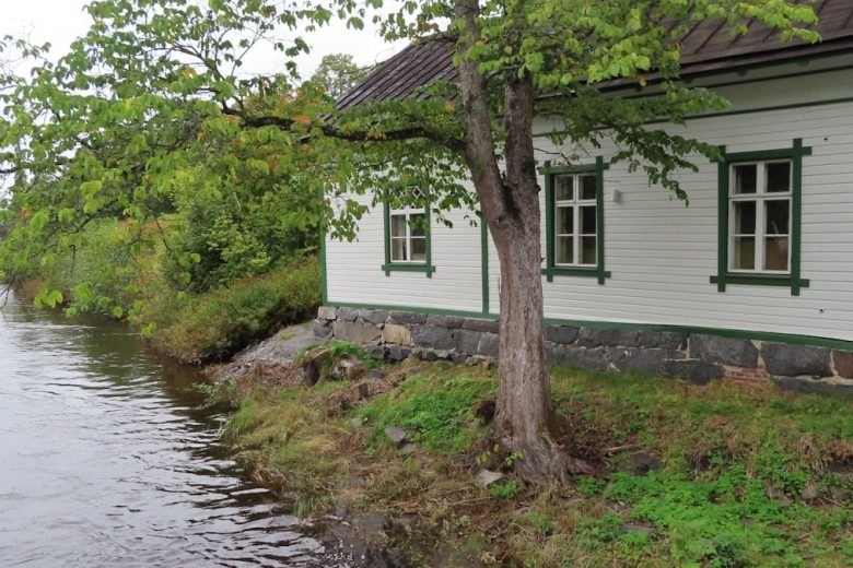 a small white house sitting next to a river